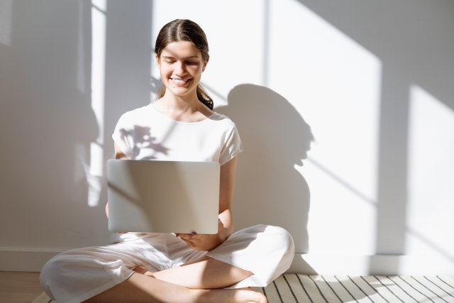 Ausbildung - Frau mit Laptop sitzt auf Fußboden